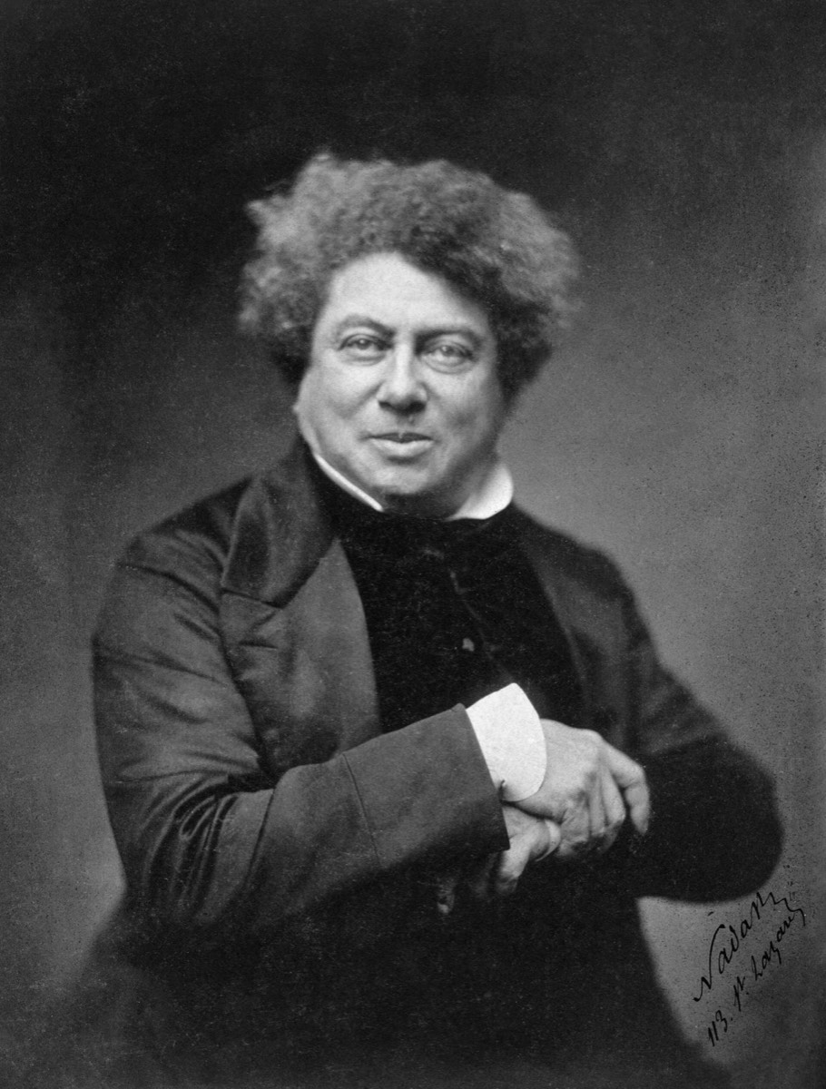 Fotografia de Alexandre Dumas por Nadar: um homem corpulento, de cabelos crespos, braços cruzados sobre o peito.